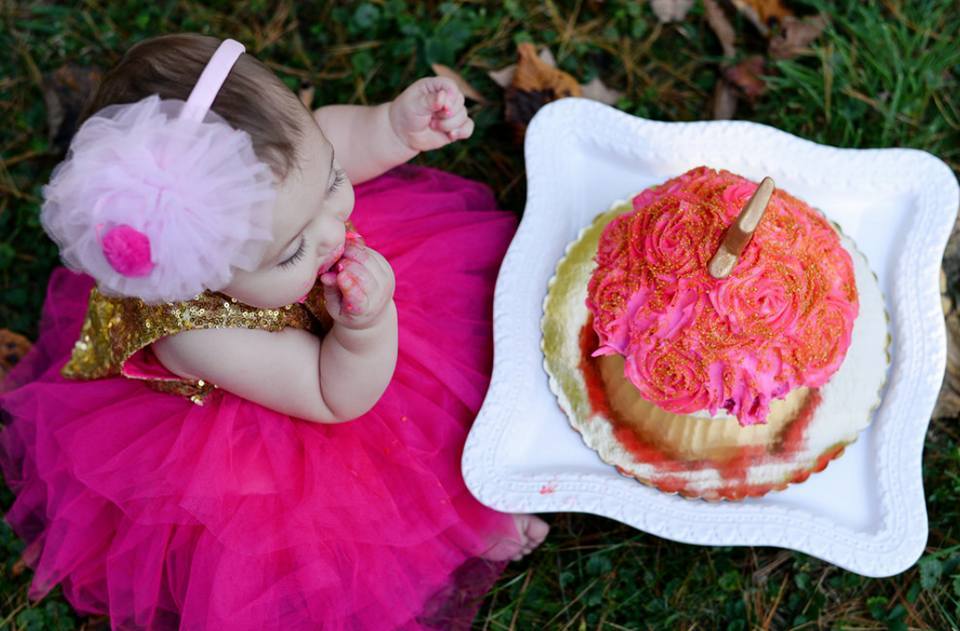 infant with flowery pink cake